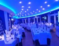 Hochzeitslocation: Unser Hauptsaal, weiße Tischdecke und Servietten, Kerzen, Blaues licht und DJ Station - Ristorante Il Pescatore