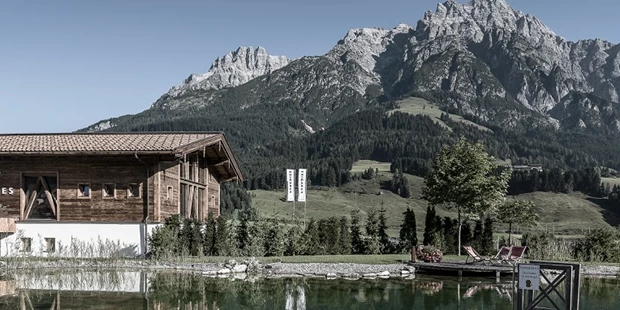 Destination-Wedding - Art der Location: Hotel / Chalet - Badhaus mit Badeteich und den Leoganger Steinbergen im Hintergrund. - PURADIES Hotel & Chalets